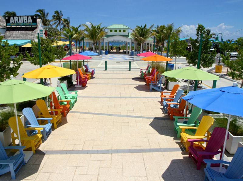 Downtown boardwalk with different brightly colored beach umbrellas and chairs.